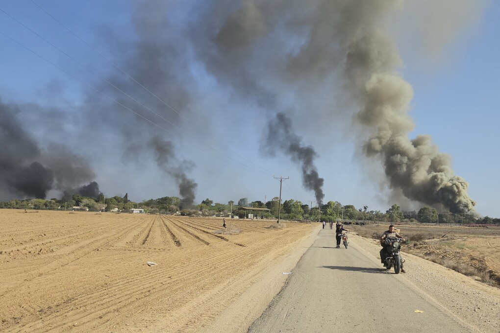 Palestinians walk away from a kibbutz, near the border fence with the Gaza Strip, while carrying out a deadly cross-border attack in southern Israel on Saturday, Oct. 7, 2023. (AP Photo)